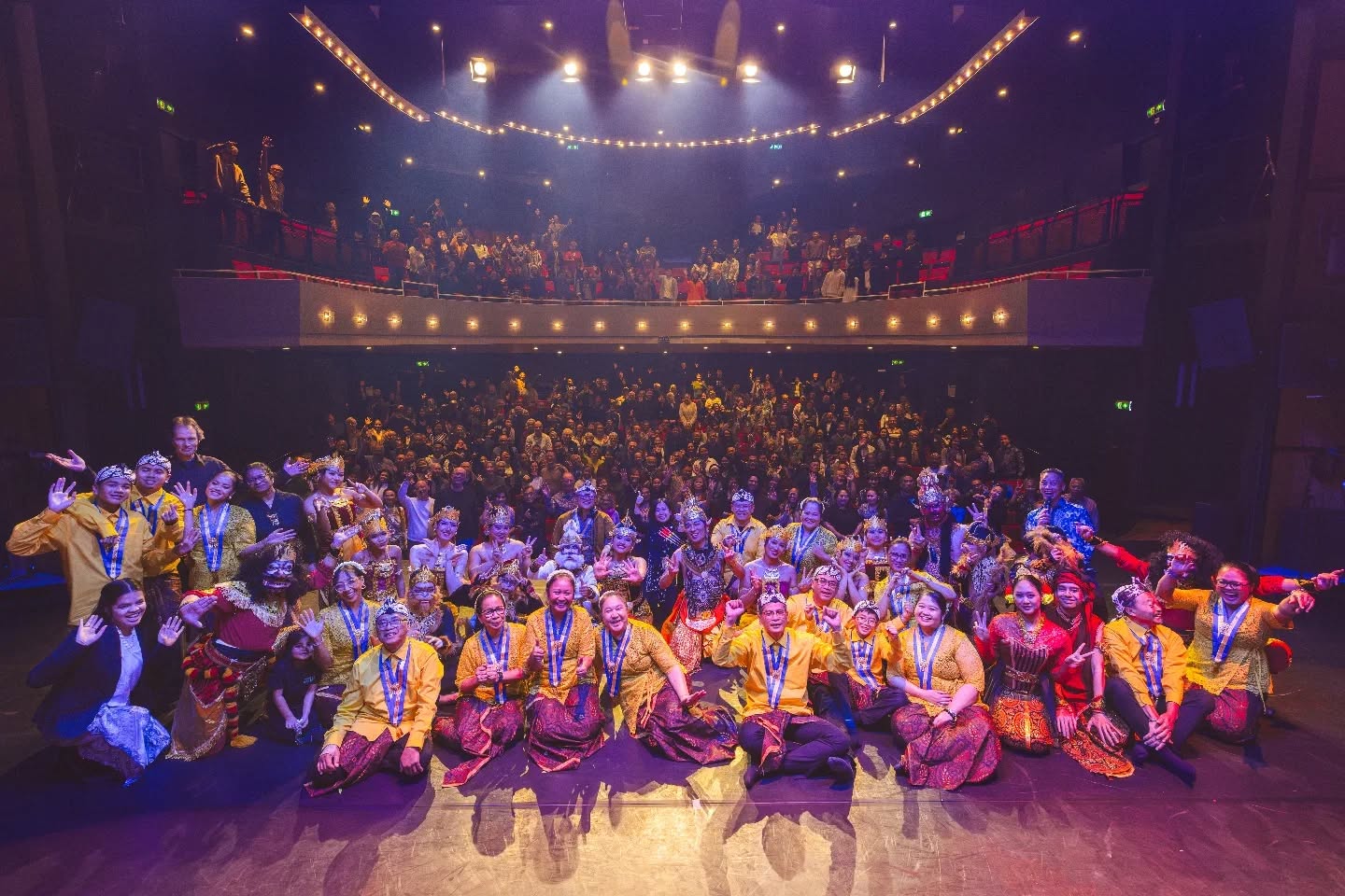 Spelers in Javaanse kostuums op het podium voor een volle zaal